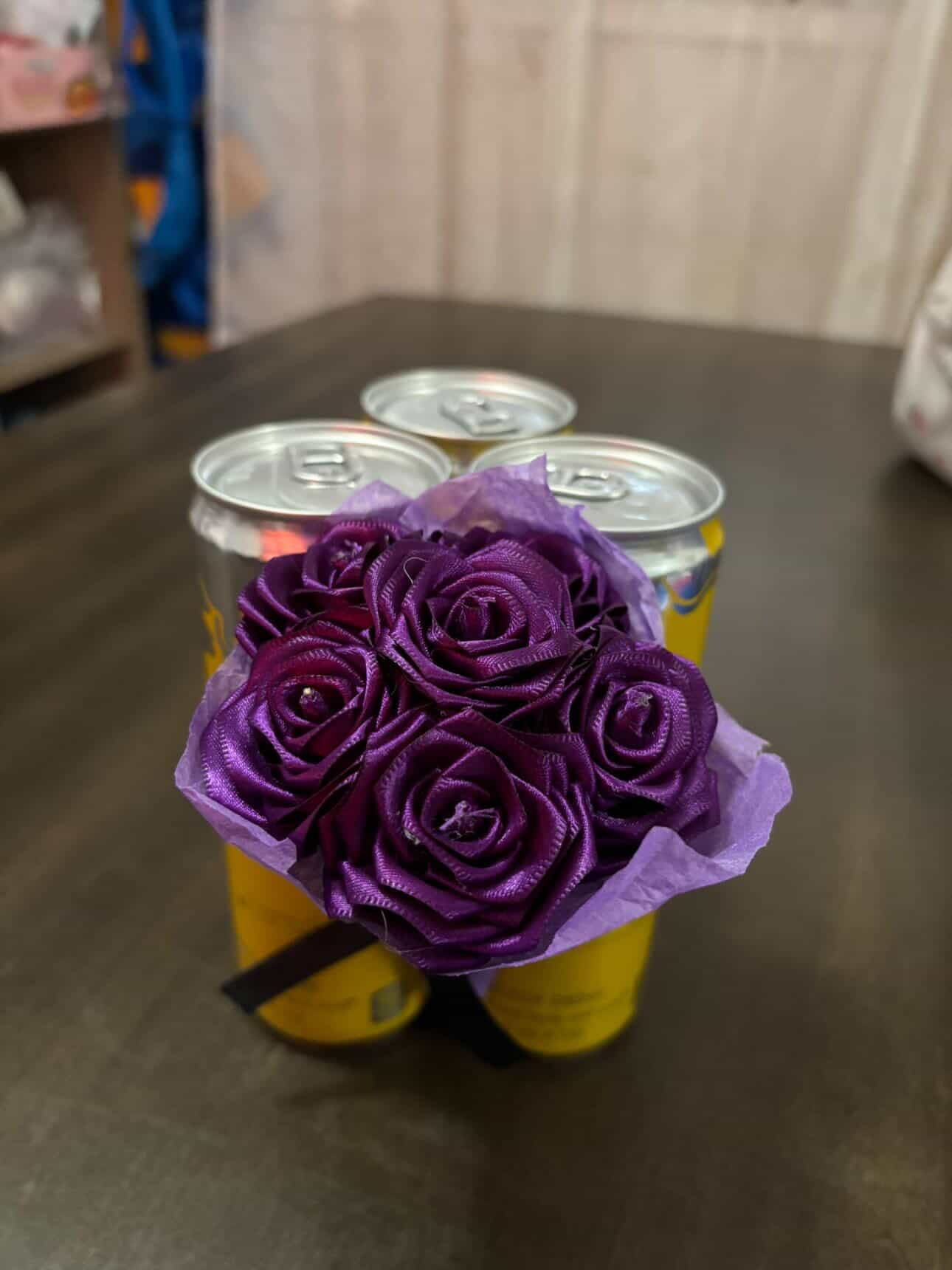 Purple ribbon roses wrapped with energy drink cans